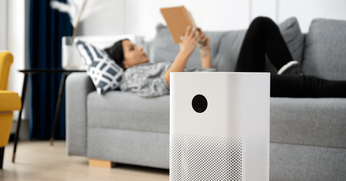 mulher lendo deitada no sofa perto do purificador de ar